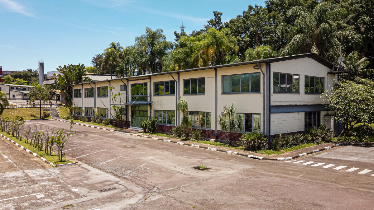 predio administrativo de 2 andares, ao fundo árvores e céu azul.