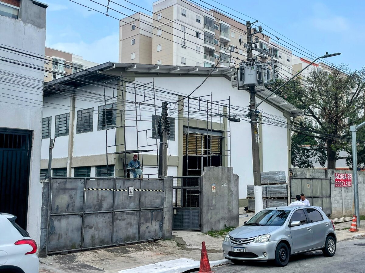 Vista externa do galpão, com condomínio residencial aos fundos
