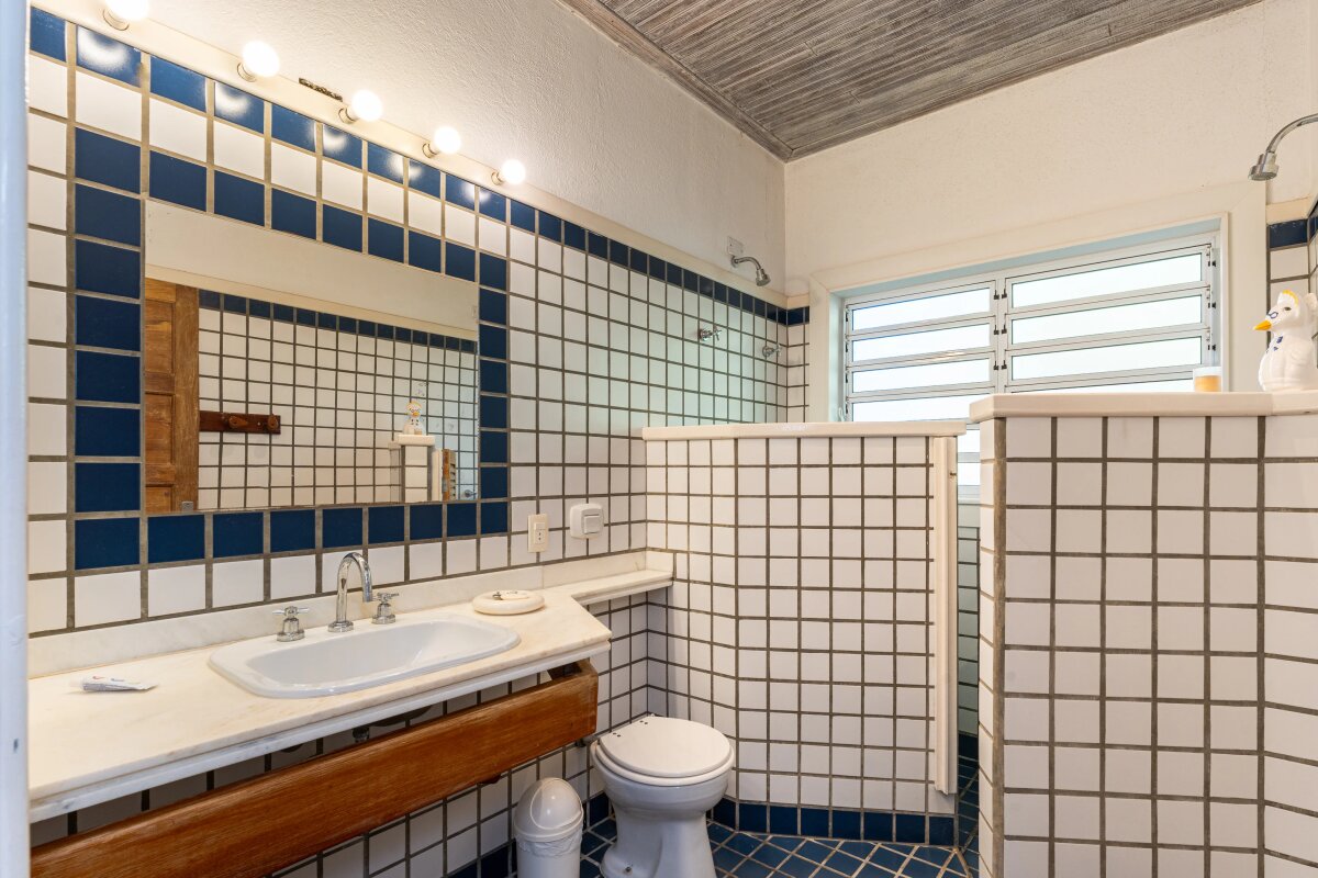 Banheiro com azulejos quadradinhos e acabamentos em azul.